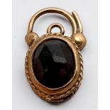 A 9ct yellow gold padlock, set with a faceted garnet to the front, and a smaller garnet to the back,