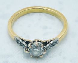 An 18ct yellow gold and platinum ring, claw set with a round brilliant cut diamond to the centre,