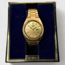A gents gold-plated Seiko 5 automatic wristwatch, the gilt dial with batons denoting hours and day-