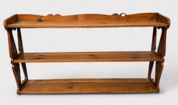 A set of waxed pine hanging open shelves, with fret-cut shaped and pierced ends, shaped pendiment