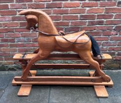 A carved pine child's rocking horse with pine stand and iron cradle, leather bridle and glass