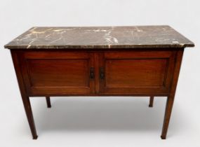 An Edwardian stained walnut wash stand with marble top above a pair of cupboard doors, raisen on