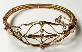 A 9ct yellow gold open-work design hinged- bangle, with safety chain, weighs 14.5 grams
