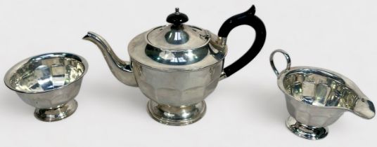 A George V three-piece silver teaset of circular panelled form on circular spreading foot, the