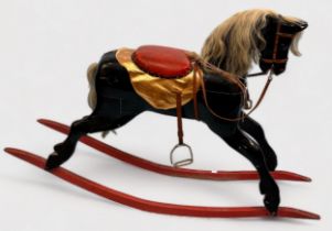 A Child's full-size wooden rocking horse, black with white mane and tail, red leather saddle and