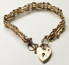 A 9ct yellow gold four-bar gate bracelet, with heart padlock and safety chain, weighs 7.1 grams.