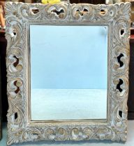 A large composit framed wall mirror, moulded with scrolling acanthus and shell-capped corners, '