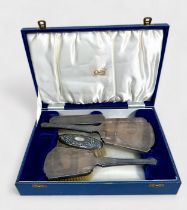 A three-piece silver hand-brush and mirror set with engine-turned decoration, in fitted gilt-
