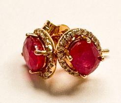 A pair of 18ct yellow gold ruby and diamond stud earrings, four-claw set with an oval ruby to the