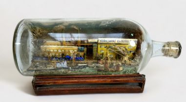 A superb diorama ship-in-a-bottle, with six various sailing barges, freighters and tugs etc, against