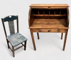 An early 20th century stained oak child's roll-top desk, with enclosed pigeonholes, short frieze