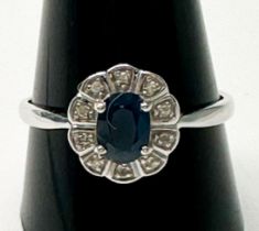 A 14ct white gold sapphire and diamond ring, claw set to the centre with an oval-shaped sapphire,