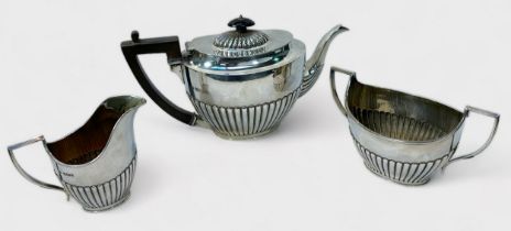 An Edwardian three-piece silver tea-set by Martin, Hall & Co. of oval form with vertical half-reeded