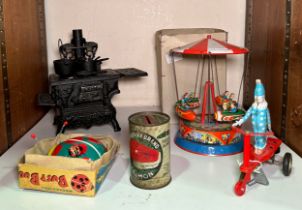 Three clockwork tinplate toys comprising a spinning rockets ride, clown riding a scooter, and a
