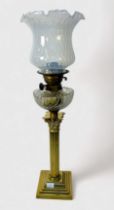A brass oil lamp modelled as a classical column, with glass reservoir and shade, raised on