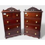 A pair of staned mahogany miniature chests of drawers, with pierced scroll-caved pediments, four