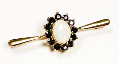 A 9ct gold bar-brooch, claw set to the centre with an oval-shaped opal, surrounded by 12 x round