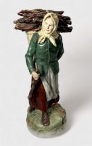 A Royal Dux pottery figure of a female 'faggot gatherer,' modelled with head-scarf and a loaded