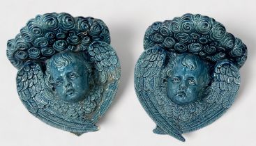 A pair of 19th century blue-blazed majolica wall brackets moulded with a winged-cherub masks, (one