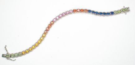 A silver tennis bracelet, claw-set with various coloured gemstones, including blue sapphires, pink