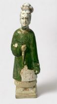A Chinese Ming Dynasty earthenware tomb figure wearing a green flowing robe, raised on pedestal,