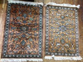 Two small machine made rugs, each with coloured geometric decoration to an orange ground, with