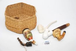 A delicately carved Meerschaum pipe in the form of a boy's head and a basket containing other pipes.