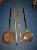 Two copper warming pans plus two wooden walking sticks.