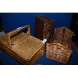 A wicker picnic basket, wine carrier and small suitcase.