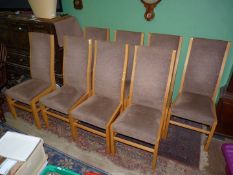 A set of seven light Oak framed high back Dining Chairs upholstered with brown fabric.