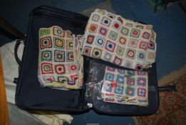 A quantity of crochet blankets in a Carlton suitcase.