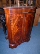 A reproduction cross banded Mahogany low Corner Cupboard having a bowed front and a pair of