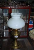 A brass Oil lamp with twin burner and white shade.
