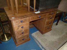 A Victorian Pine Kneehole Desk with cobalt blue ceramic and brass knobs, some locks and key,