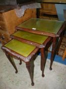 A Nest of Three Mahogany framed Occasional Tables with green inset tops and protective glass panels