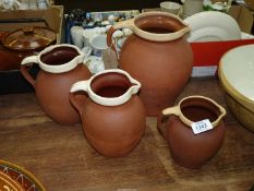 Four terracotta jugs with cream glazed rims, one with a Royal Barum ware stamp for C.H.
