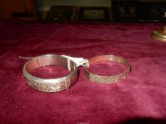 Two silver Bangles with scroll and floral designs, one with dent and safety chain broken,