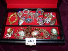 A black jewellery box containing costume jewellery including a Siam sterling brooch, a Rosary,