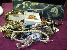 A box of miscellaneous costume jewellery including brooches, faux pearl and bead necklaces,