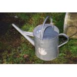 A large galvanised watering can.