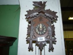 A traditional Cuckoo clock having hand carved bird and leaf detail, with pendulum.