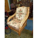 A cane/bamboo framed Conservatory Armchair having loose cushions upholstered in stylised floral