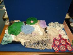 A quantity of crocheted pieces including coasters, table mats, small tablecloths in green, red,