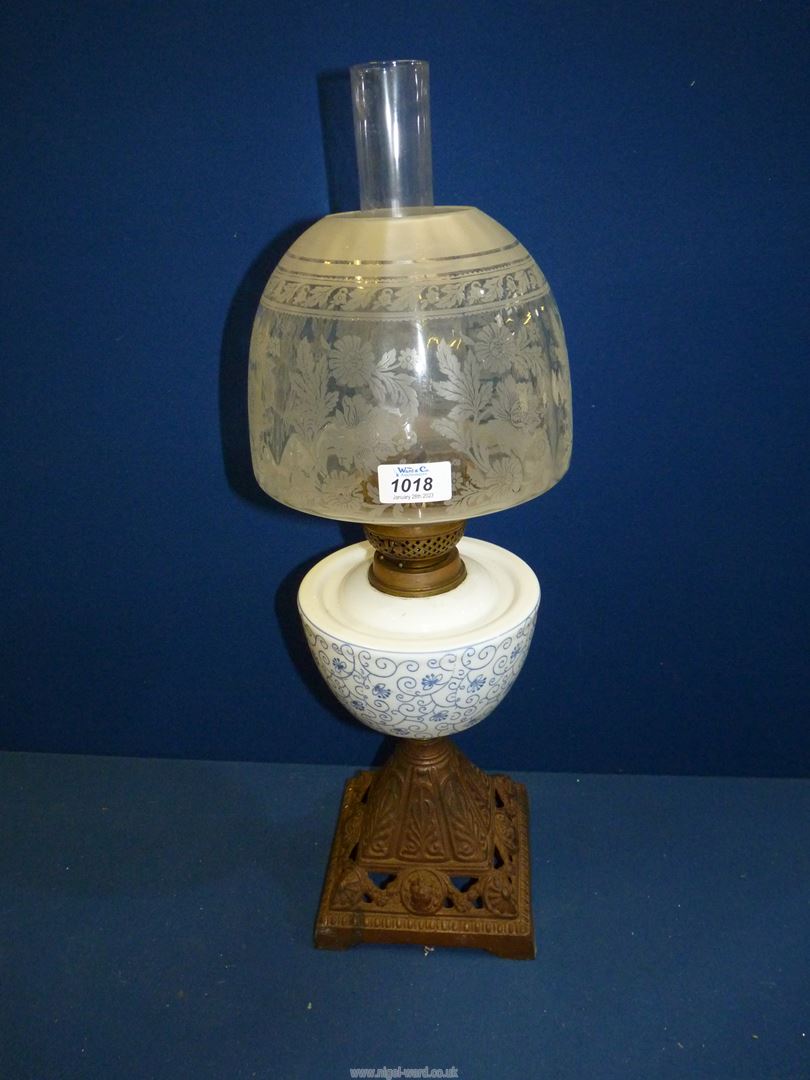 An Oil lamp having cast base, blue and white china reservoir and etched shade, plus chimney.