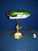 A brass Bankers lamp with green glass shade.