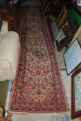 A Carpet Runner in cream and red floral pattern, 14'6'' long x 2'5'' wide.