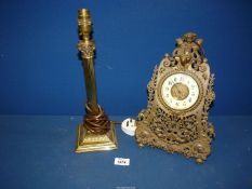 A brass Corinthian column lamp base and an ornate brass table Clock with cherub detail, key present.