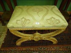 An upholstered Footstool on ornate gold painted legs and with upholstered seat with applied