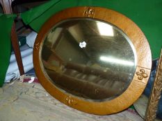 An oval bevel edged Mirror with wooden surround having fleur-de-lys pattern.