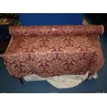 A large roll of floral burgundy ground upholstery fabric, 56" wide, approx. 8 - 10 metres.